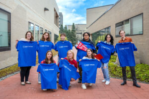 A group of students pose together holding blue tshirts