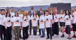 Members of the first Empire State Service Corps cohort all wearing ESSC tshirts stand outside with SUNY Chancellor John King and Lieutenant Governor Delgado.