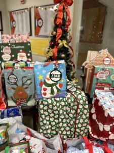 Gifts in colorful bags and wrapping paper sit near a tree at SUNY New Paltz