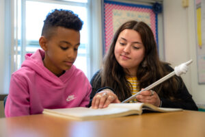 Teacher assisting a student with reading