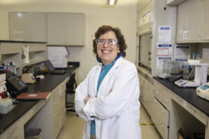 Professor Susan Sharfstein standing in a research lab wearing a white lab coat.
